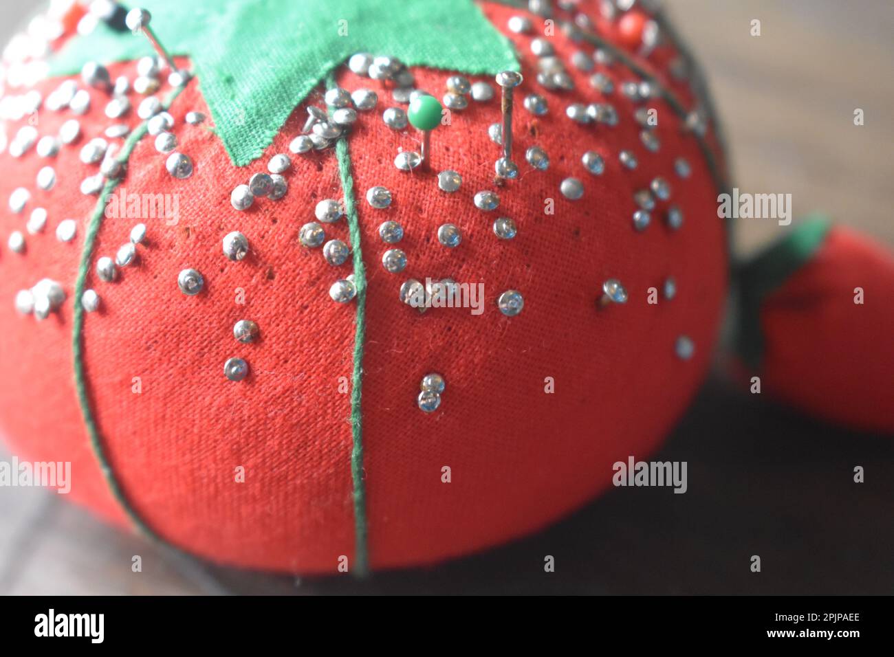 A vintage pin cushion for sewing pins, tomato cushion with strawberry emery pin sharpener Stock
