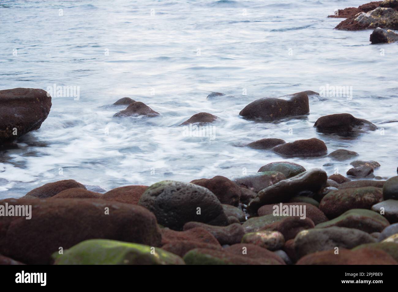 A scenic landscape featuring large rocks and rippling water in dark ...
