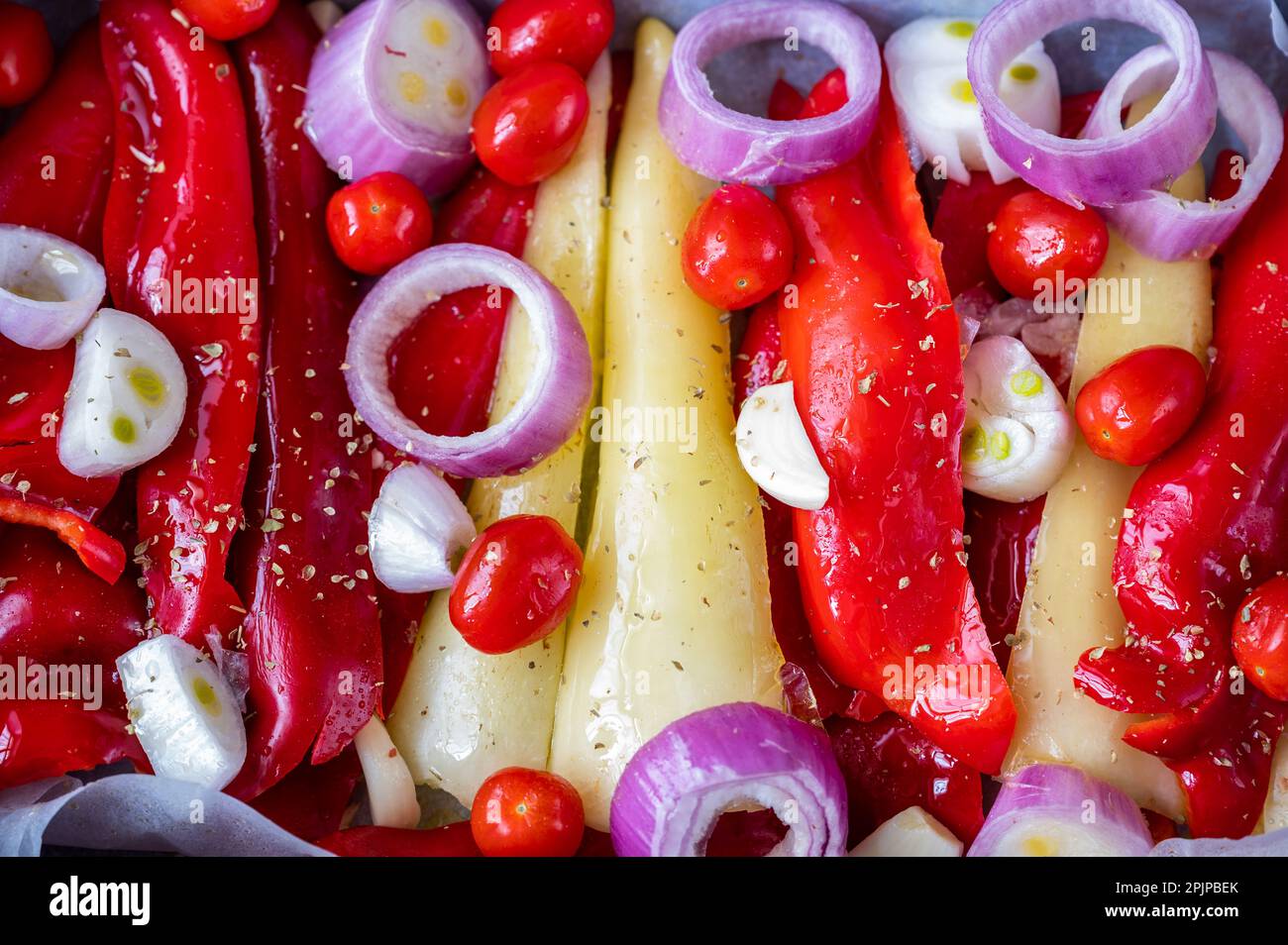 Sliced red and yellow pepper, onion circle, cherry tomato and garlic, preparation of food. Stock Photo