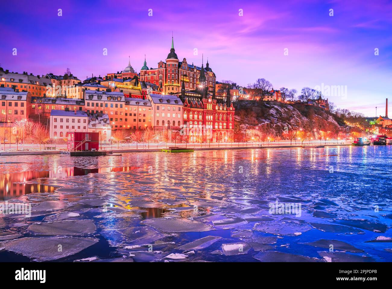 Stockholm, Sweden. Mariaberget and Sodermalm island in winter. Beautiful orange, violet and pink sky at twilight, reflected in frozen water of lake Ma Stock Photo