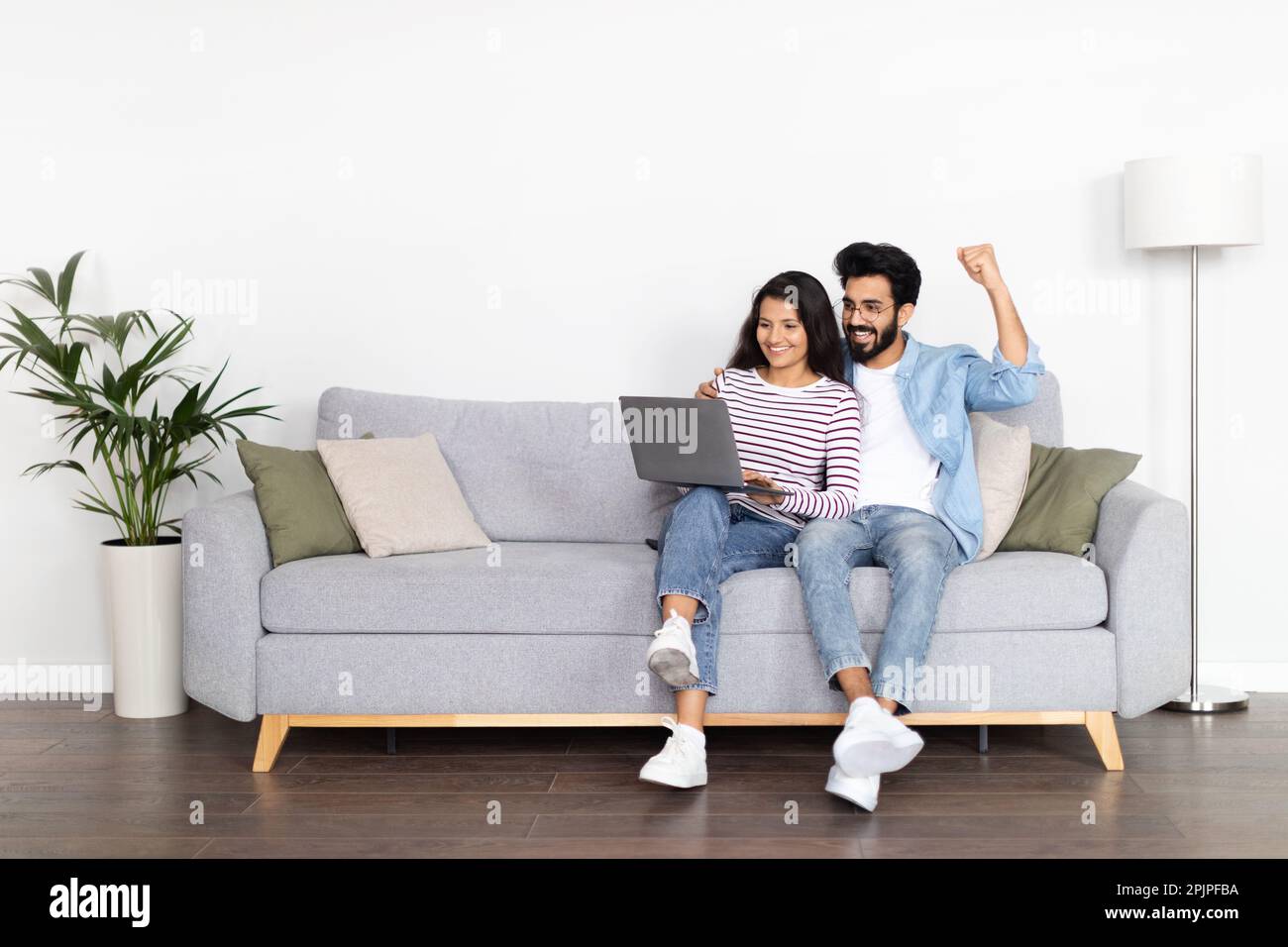 Positive interracial young man and woman using computer at home Stock Photo