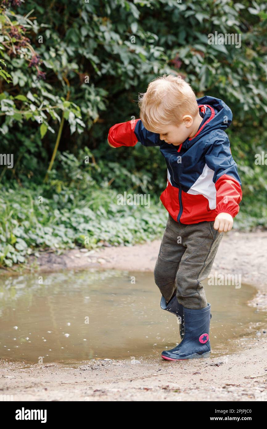Little boy splashing in a mud puddle. Stock Photo