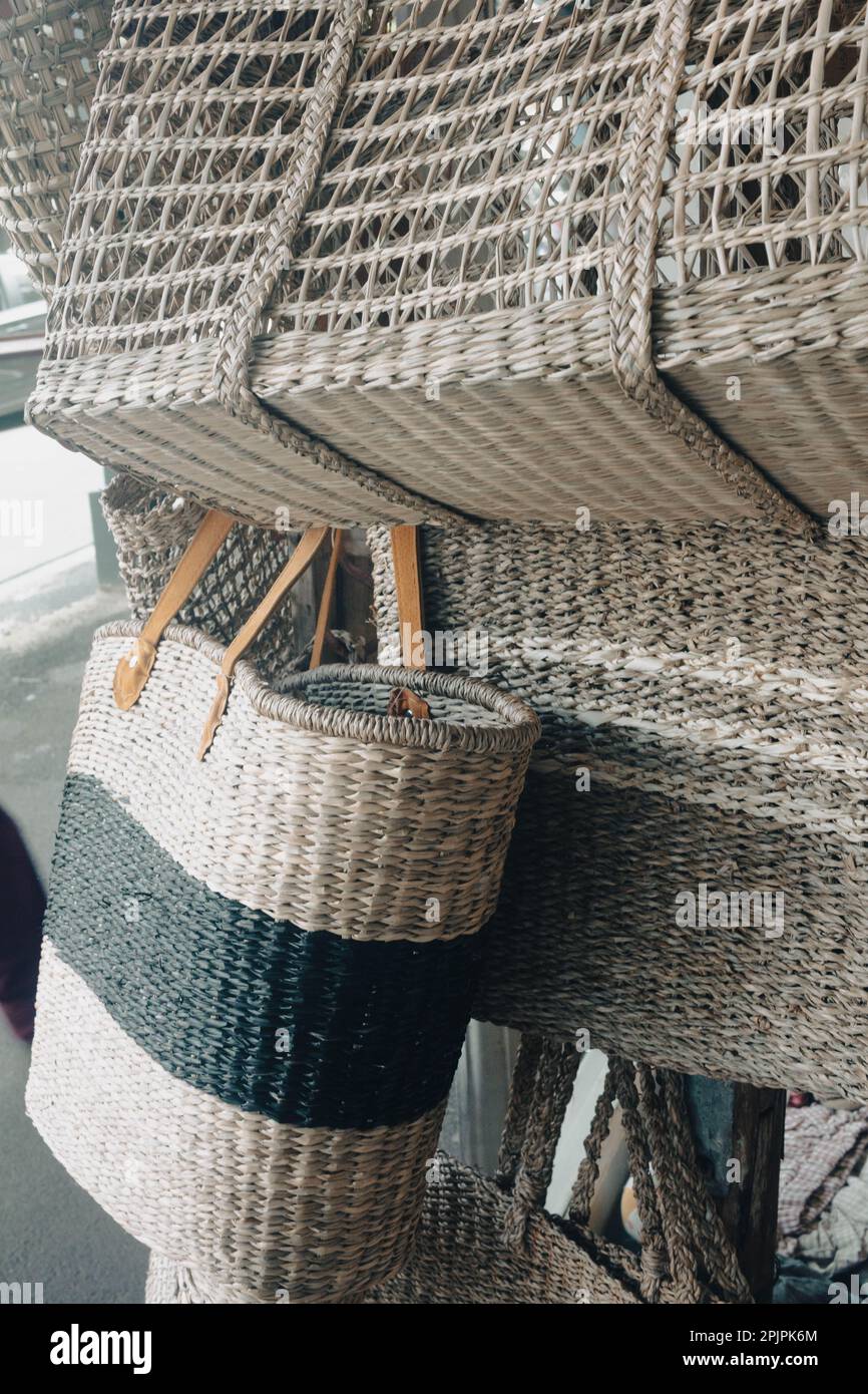 An old-fashioned wicker basket suspended from a wooden ladder on a wall Stock Photo