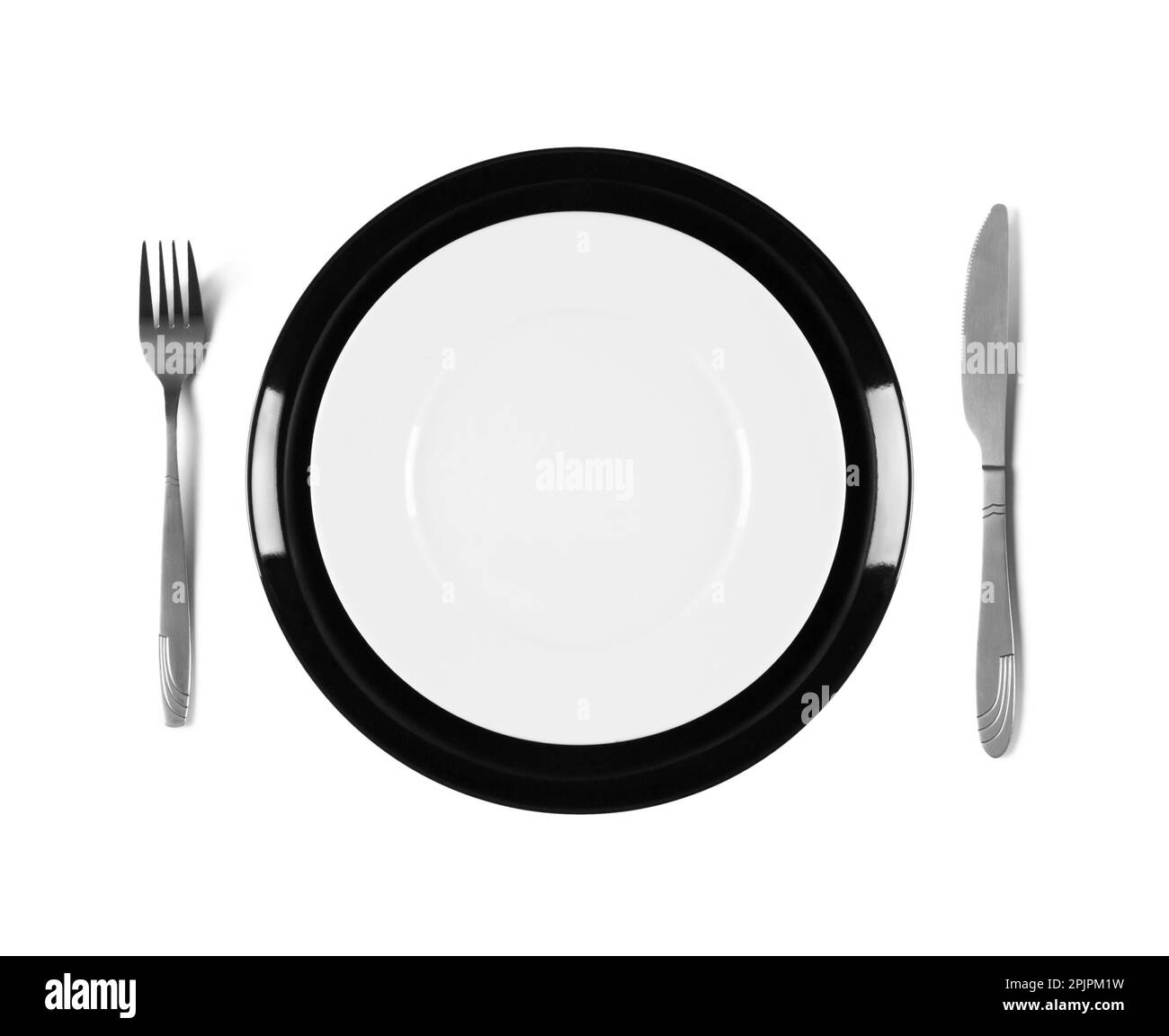 Two stacked black and white plates with fork and knife, isolated on white background Stock Photo