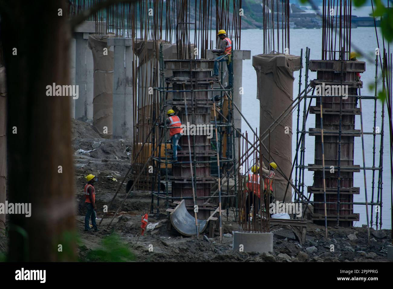 Construction workers busy build pillars of a bridge in the banks of ...