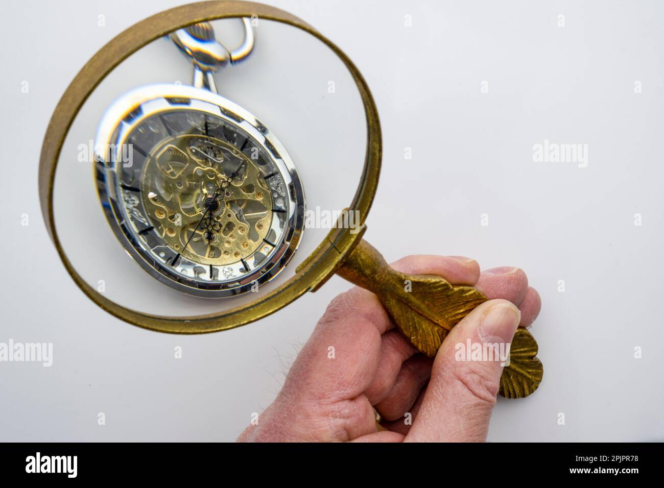 A hand holding a magnifying glass examining a pocket watch with visible  gears, isolated on white background, concept time management Stock Photo -  Alamy