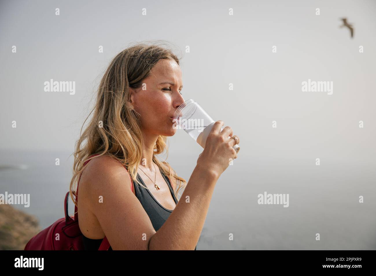A female hiker drinks water during a hike, concept of hydration and health. Stock Photo