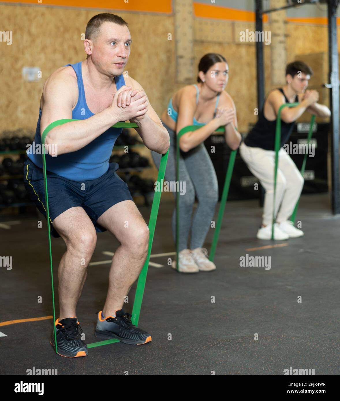Motivated man practicing exercises with stretch rope standing near ...