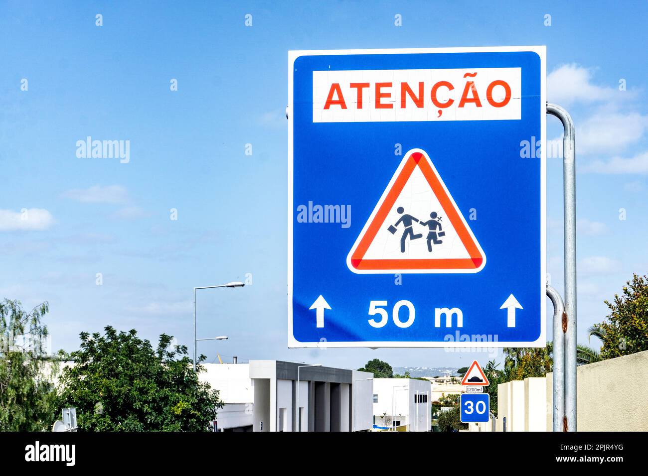 A Portuguese language, warning road sign, to advise that children are crossing the road, school nearby. Stock Photo