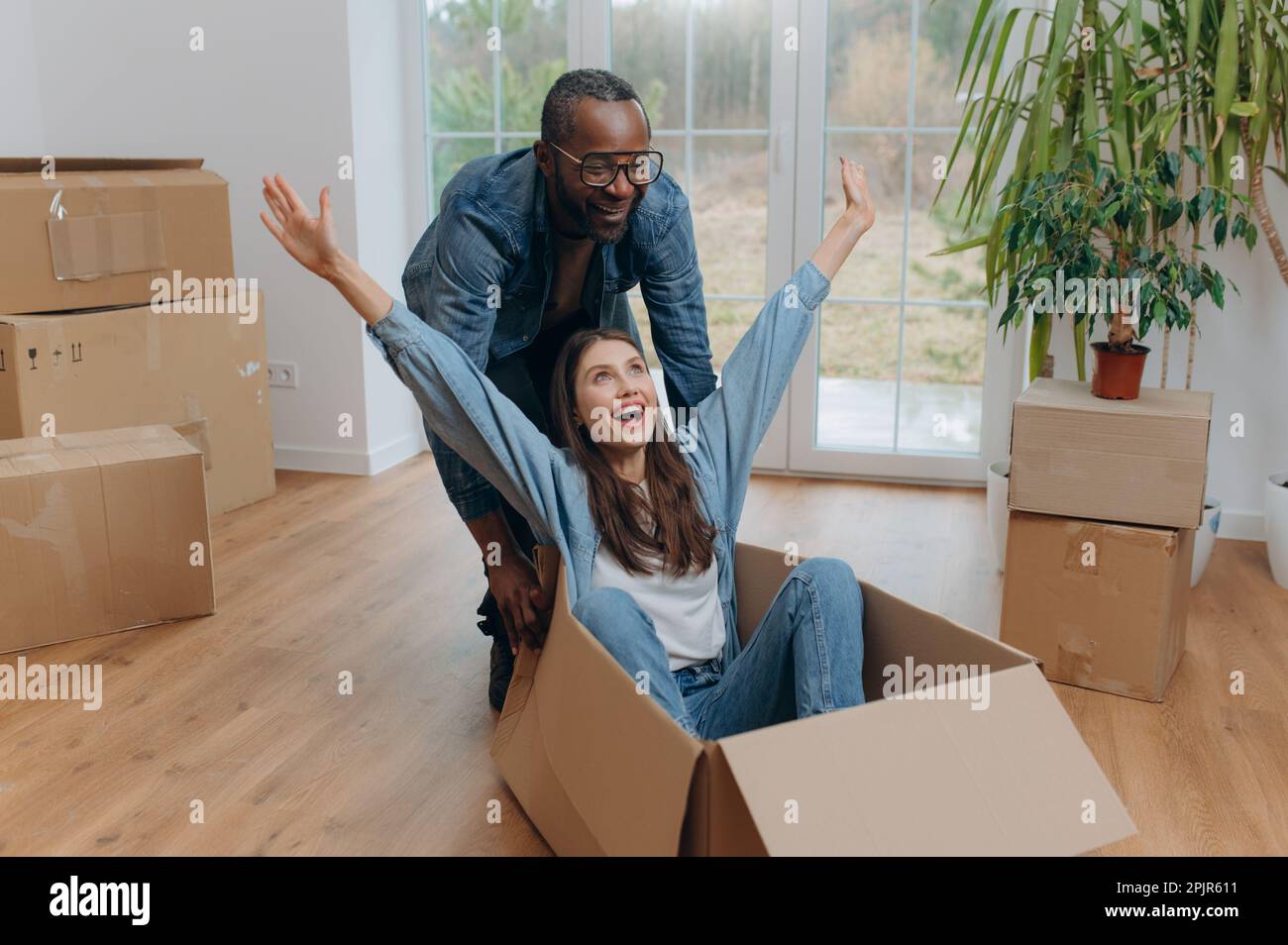 A happy interracial couple, unpacking and laughing on moving day. A ...