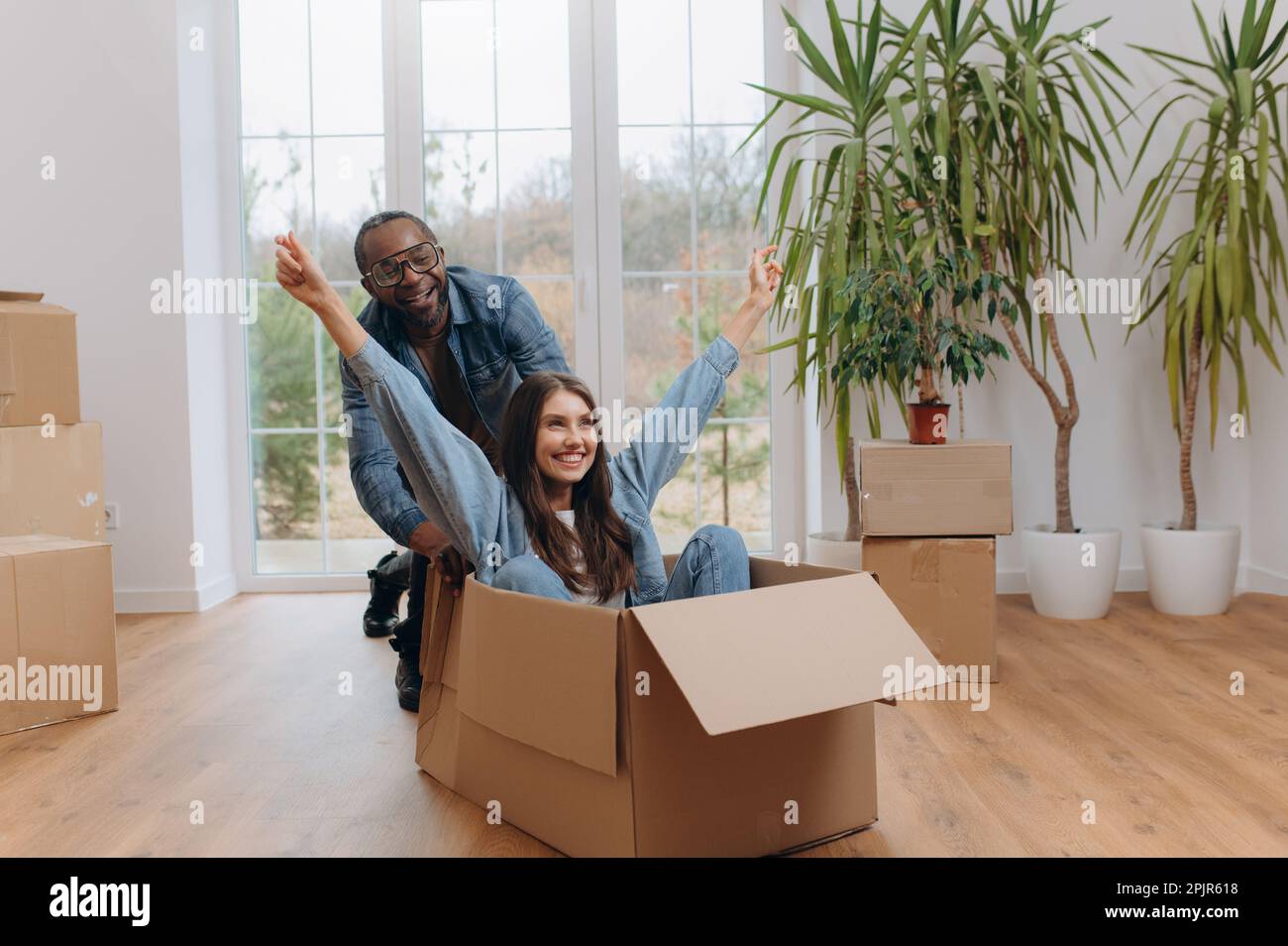A happy interracial couple, unpacking and laughing on moving day. A ...