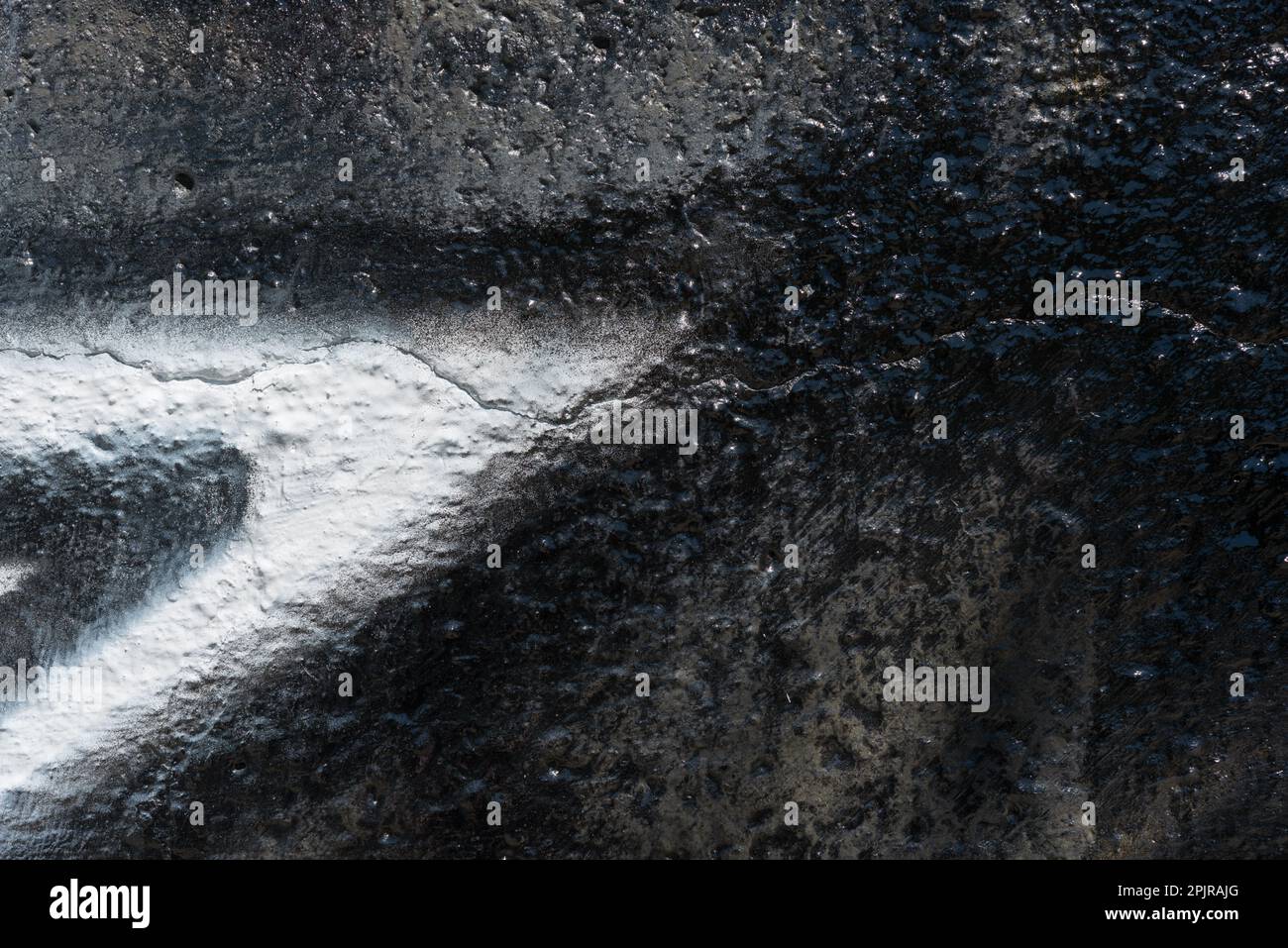 rough retaining wall painted with shiny black paint and a spray painted