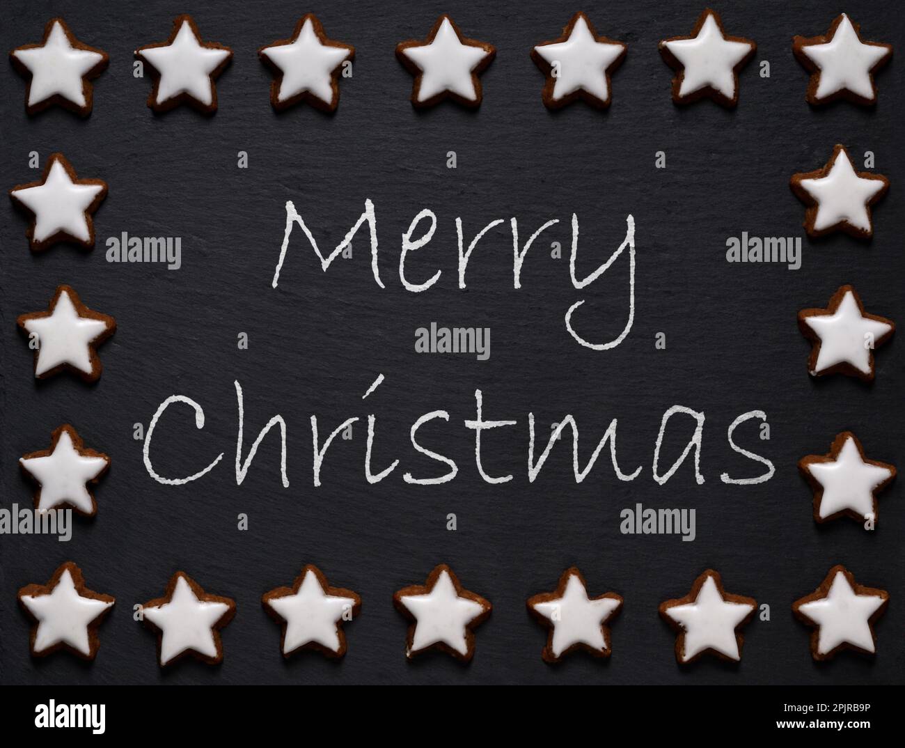 merry christmas written on slate with star shaped cookie decoration Stock Photo
