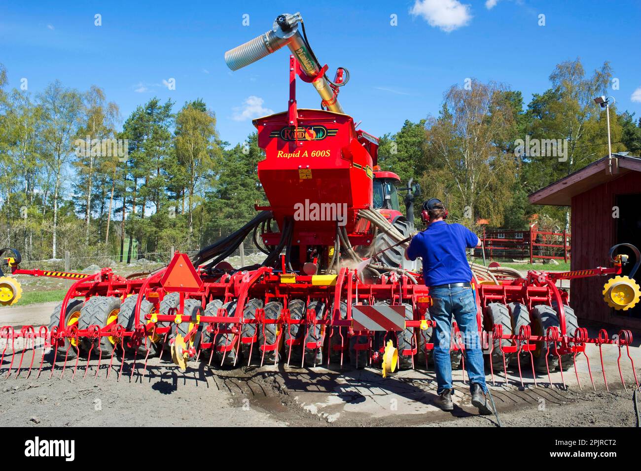 Farmer washes Vaderstad Rapid A 600S seed drill with high-pressure cleaner, Upplands Vasby, Sweden Stock Photo