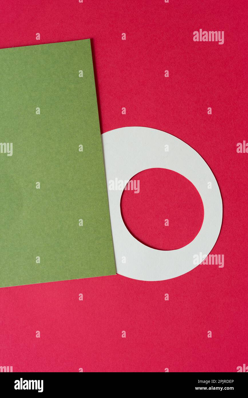 round paper shape with hole and green card on a red background Stock Photo
