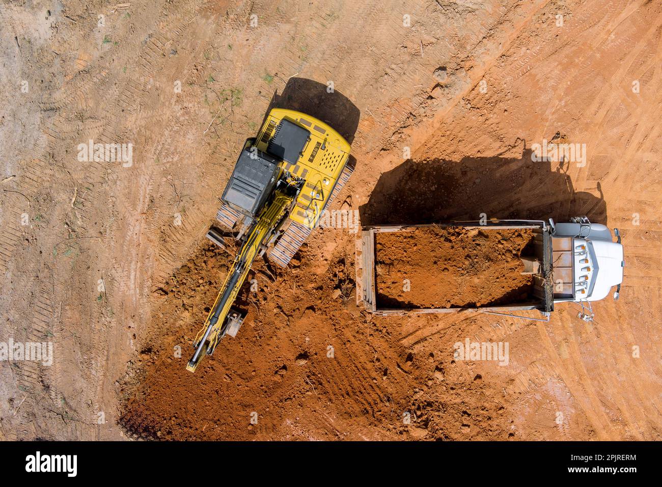Excavator operator is carefully positioning scoop on soil is into
