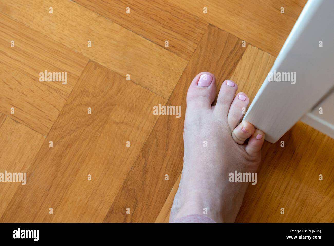 Woman hit furniture with the little toe. Incident at home. Injury of foot little finger Stock