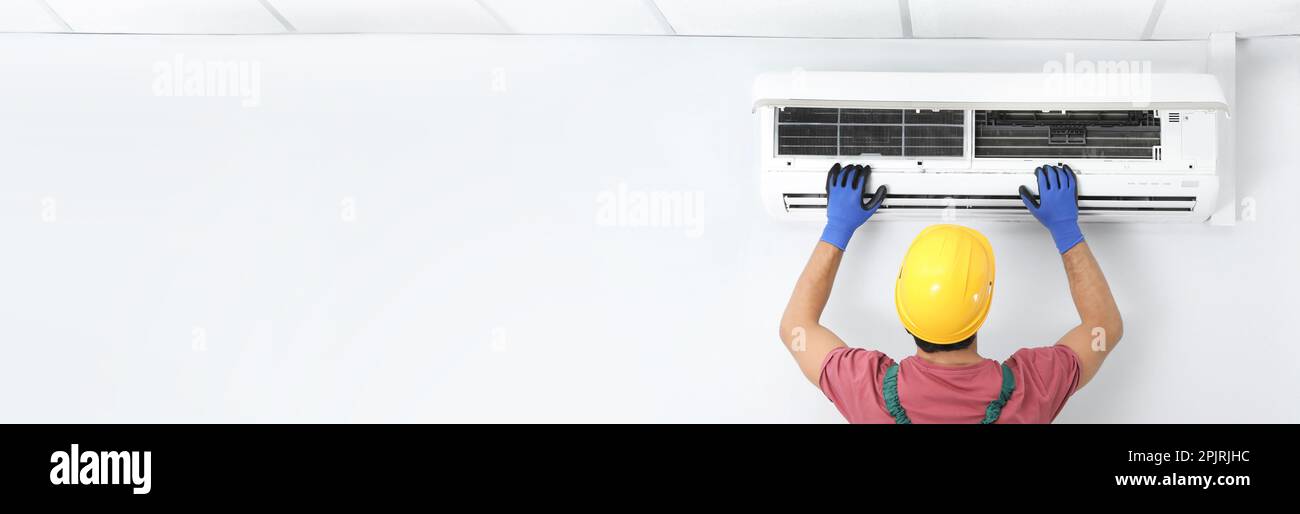 Male technician checking air conditioner indoors, space for text. Banner design Stock Photo