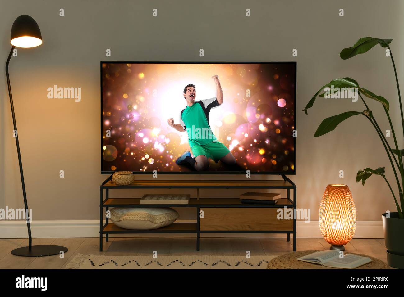 Modern TV set on wooden stand in room. Scene of football broadcasting Stock Photo