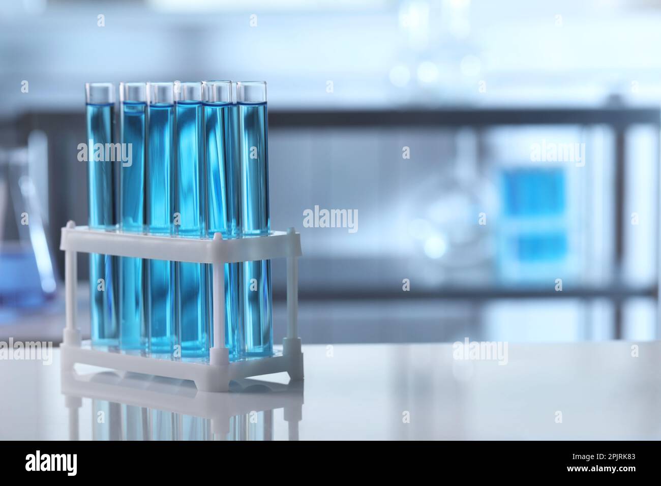 Test tubes with light blue liquid on table in laboratory. Space for ...