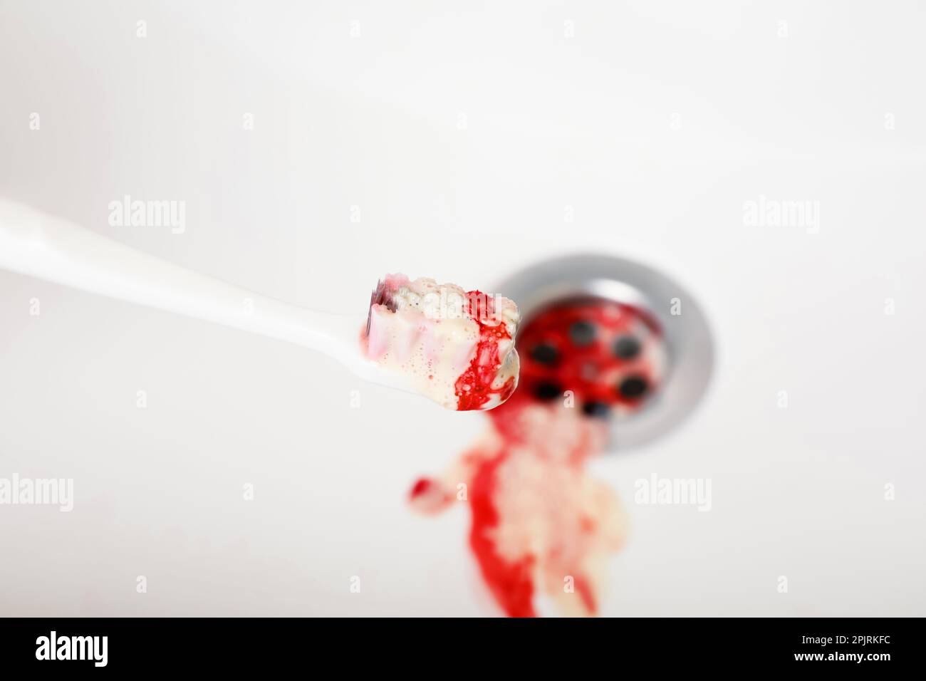 Toothbrush with paste and blood over sink, closeup. Gum inflammation Stock Photo