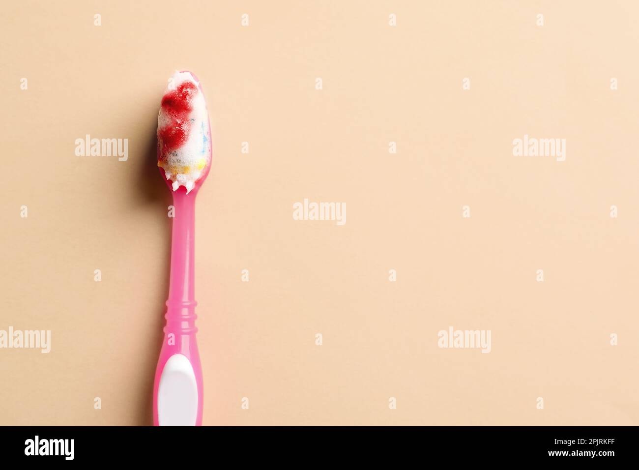 Toothbrush with blood on beige background, top view and space for text