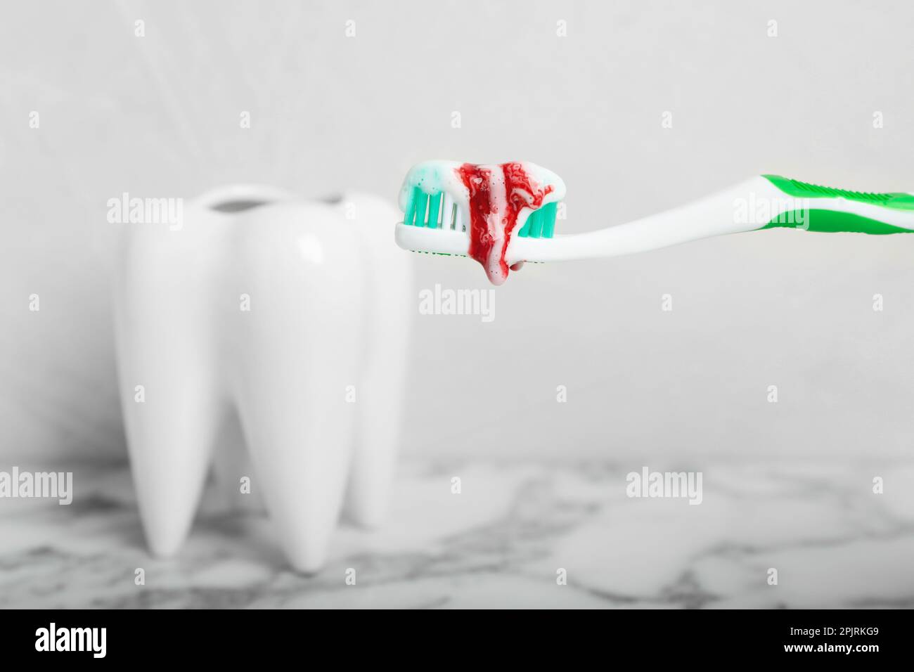 Toothbrush with paste and blood near tooth model, space for text. Gum