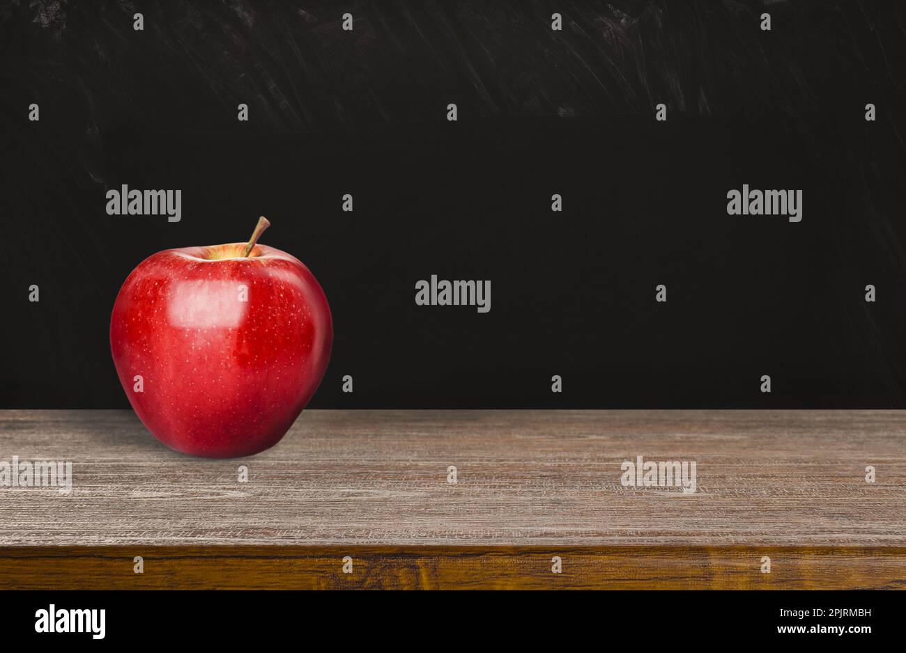 Fresh ripe red apple on wooden table near black chalkboard, space for text Stock Photo