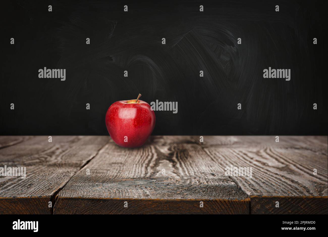 Fresh ripe red apple on wooden table near black chalkboard, space for text Stock Photo