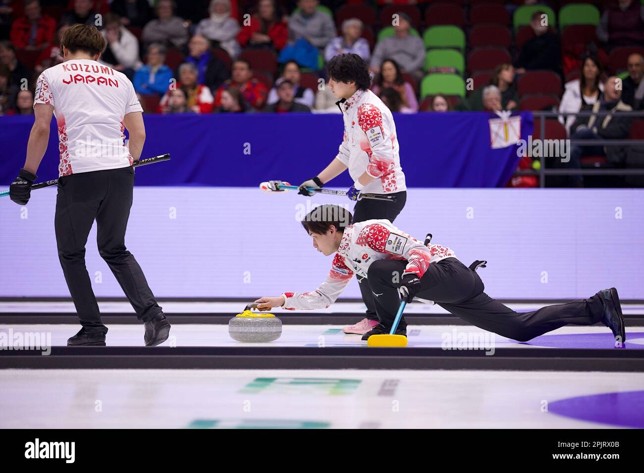 Riku Yanagisawa throws a stone with Satoshi Koizumi (L) and Satoshi
