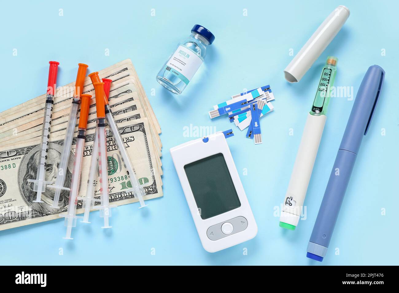 Insulin with lancet pens, syringes and money on blue