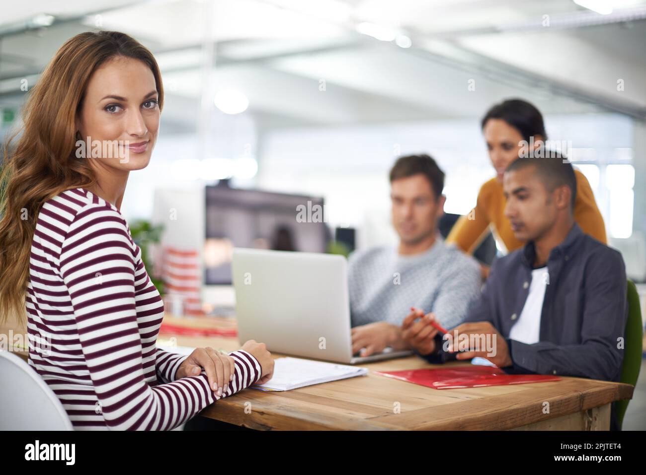 Proud of her team. A young designer smiling while her team has a ...