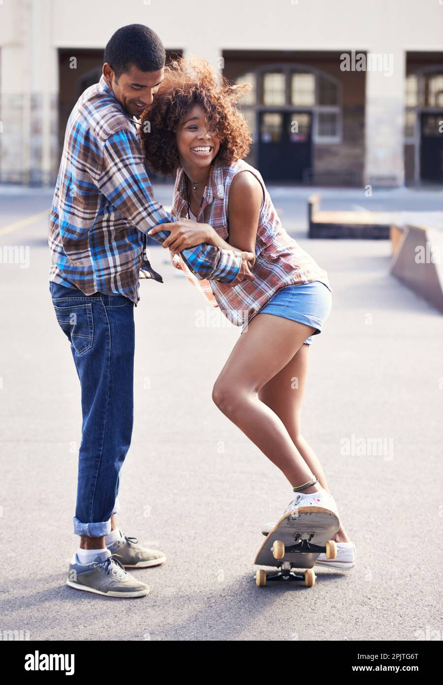 Youll get the hang of it. a young man teaching his girlfriend how to skateboard Stock Photo Alamy
