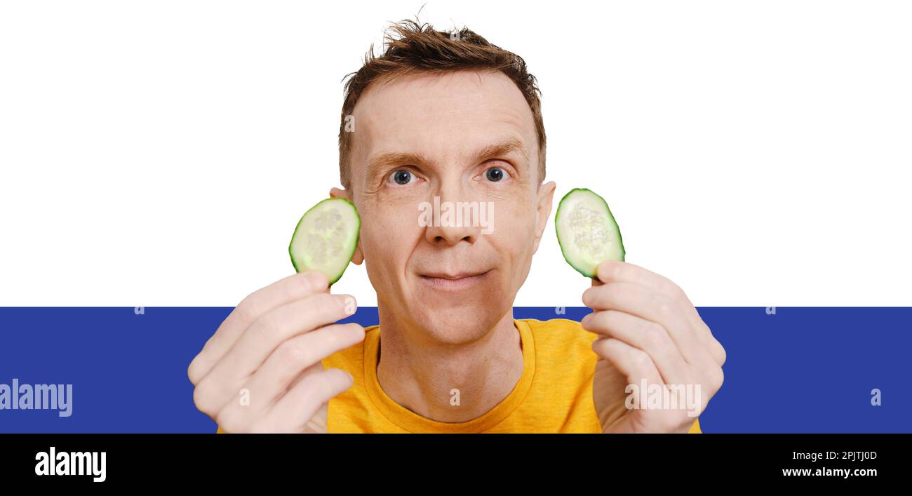 Middle-aged man holds two slices of cucumber in hands Stock Photo