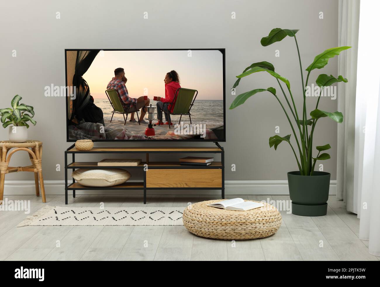 Modern TV set on wooden stand in room. Scene of romantic movie on screen Stock Photo