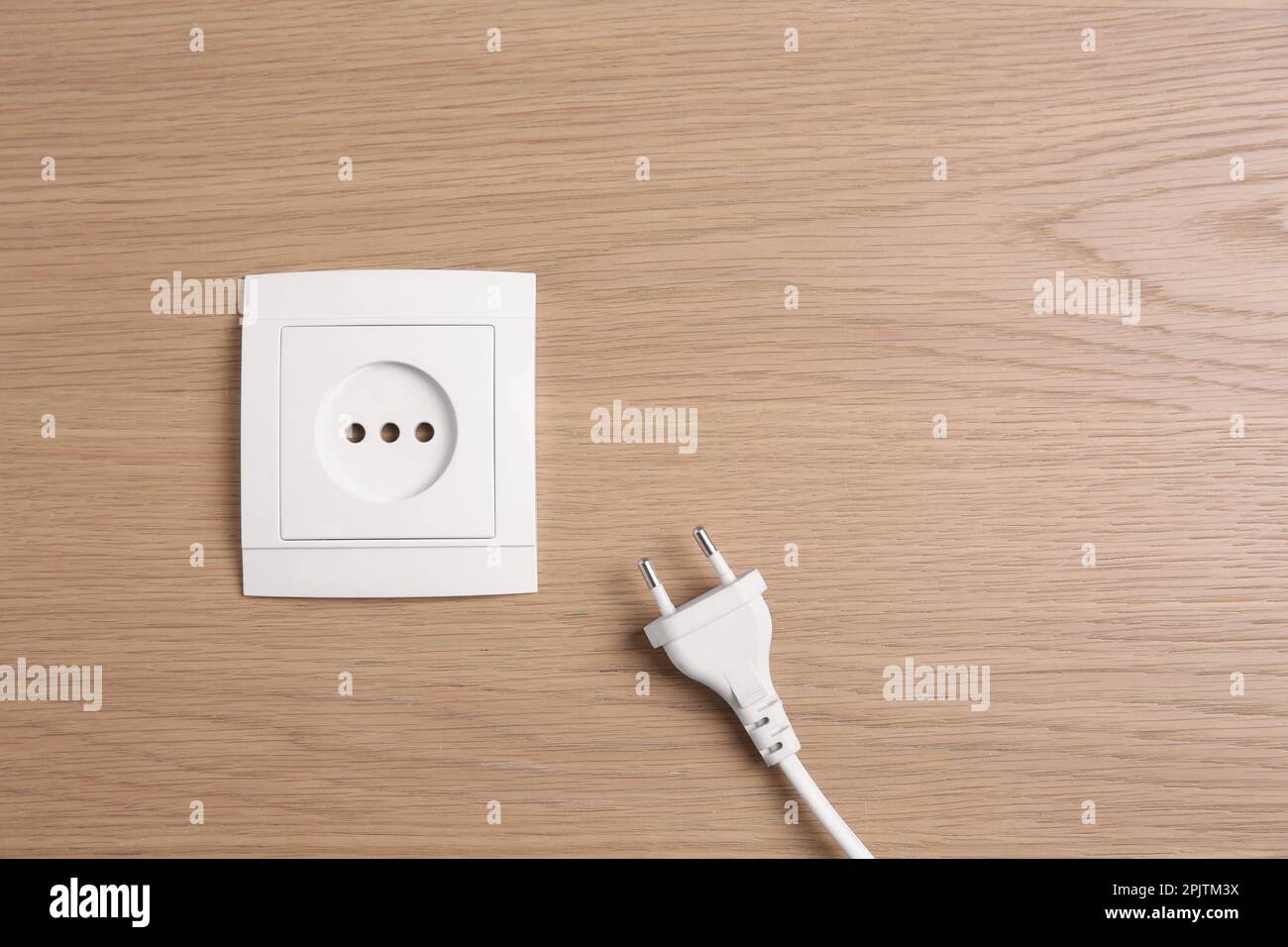 Power socket with plug on wooden table, flat lay. Space for text Stock ...