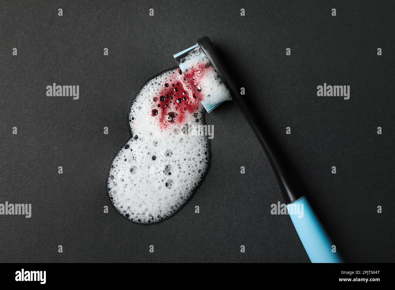 Toothbrush with paste and blood on black background, top view. Gum