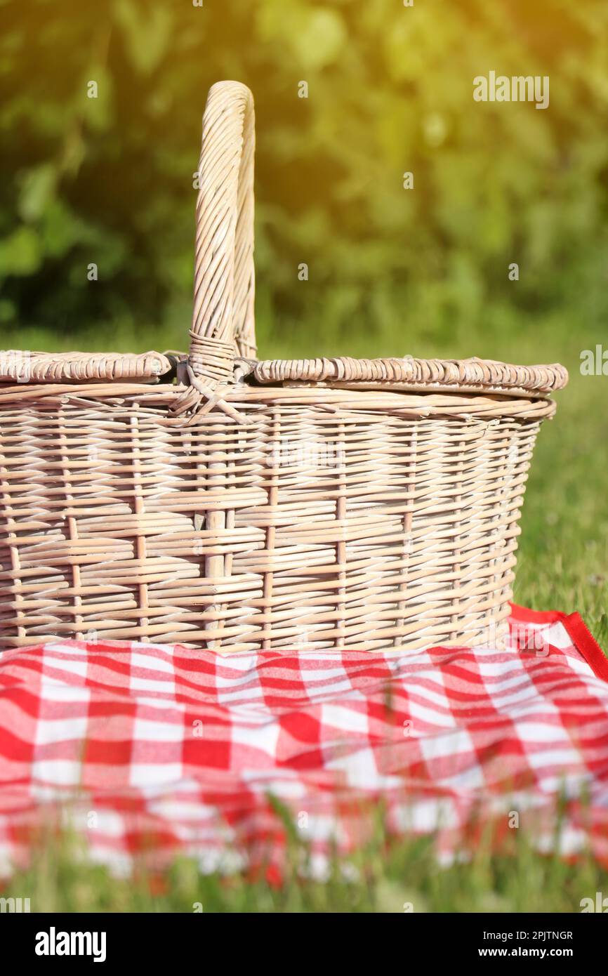 Picnic basket with checkered tablecloth on green grass outdoors Stock ...