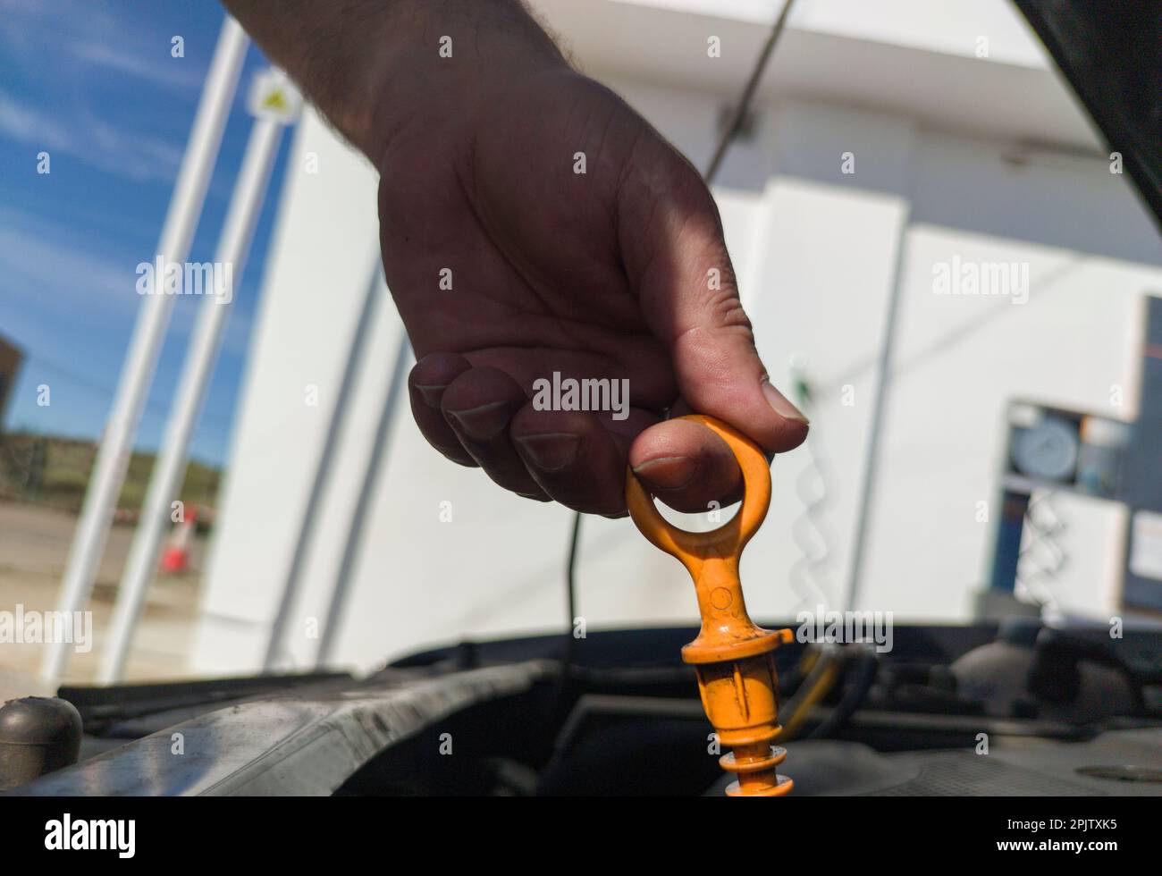 Man checking his oil level from old diesel engine. Petrol station background Stock Photo