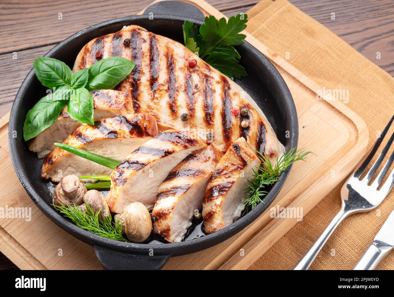 Roasted chicken fillet and mushrooms with herb in the frying pan on the wooden table close-up. Stock Photo