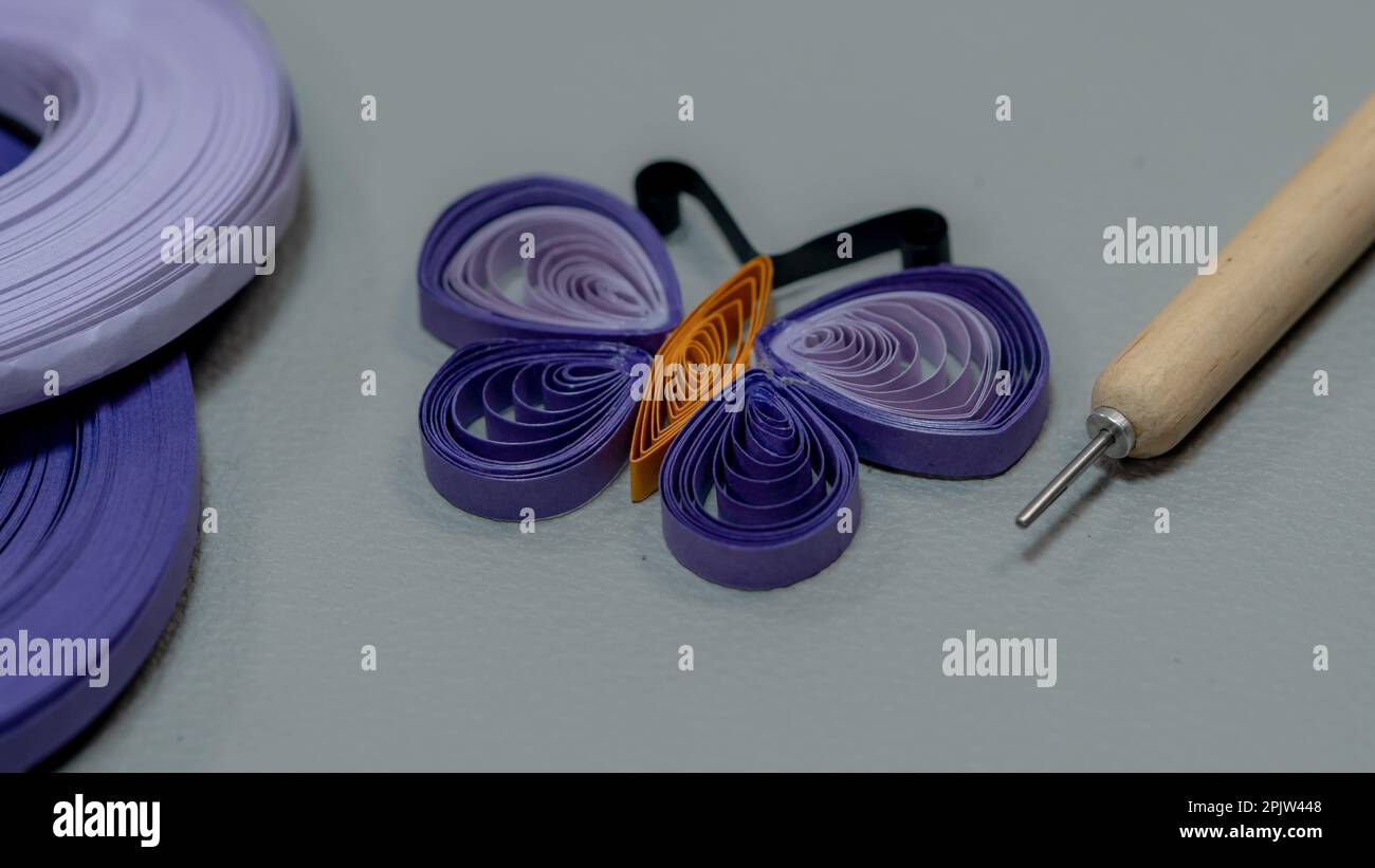 A closeup shot of a roll of purple paper butterfly and a tool Stock Photo