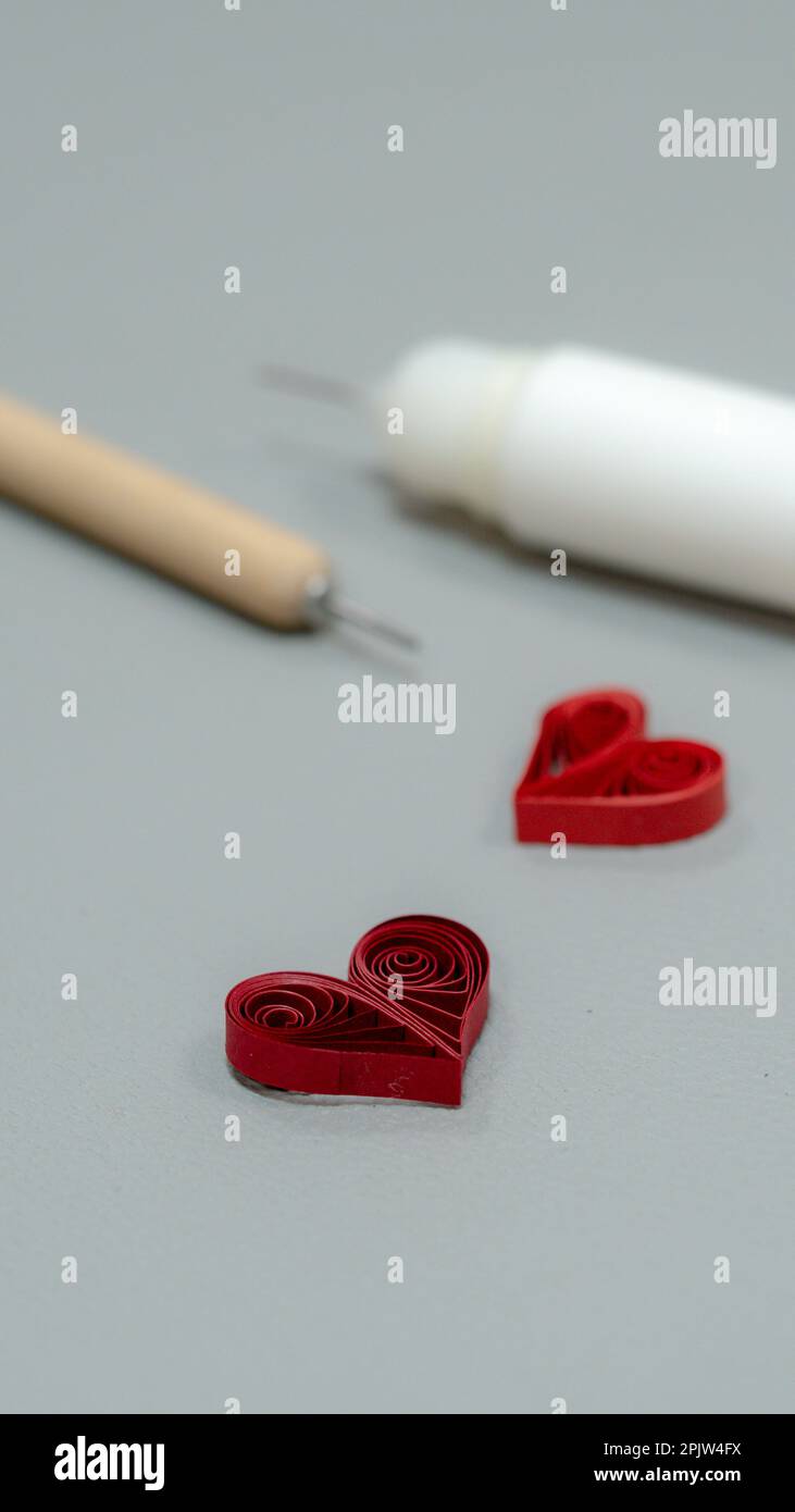 Paper quilled red heart, glue and needle on a gray background. Stock Photo