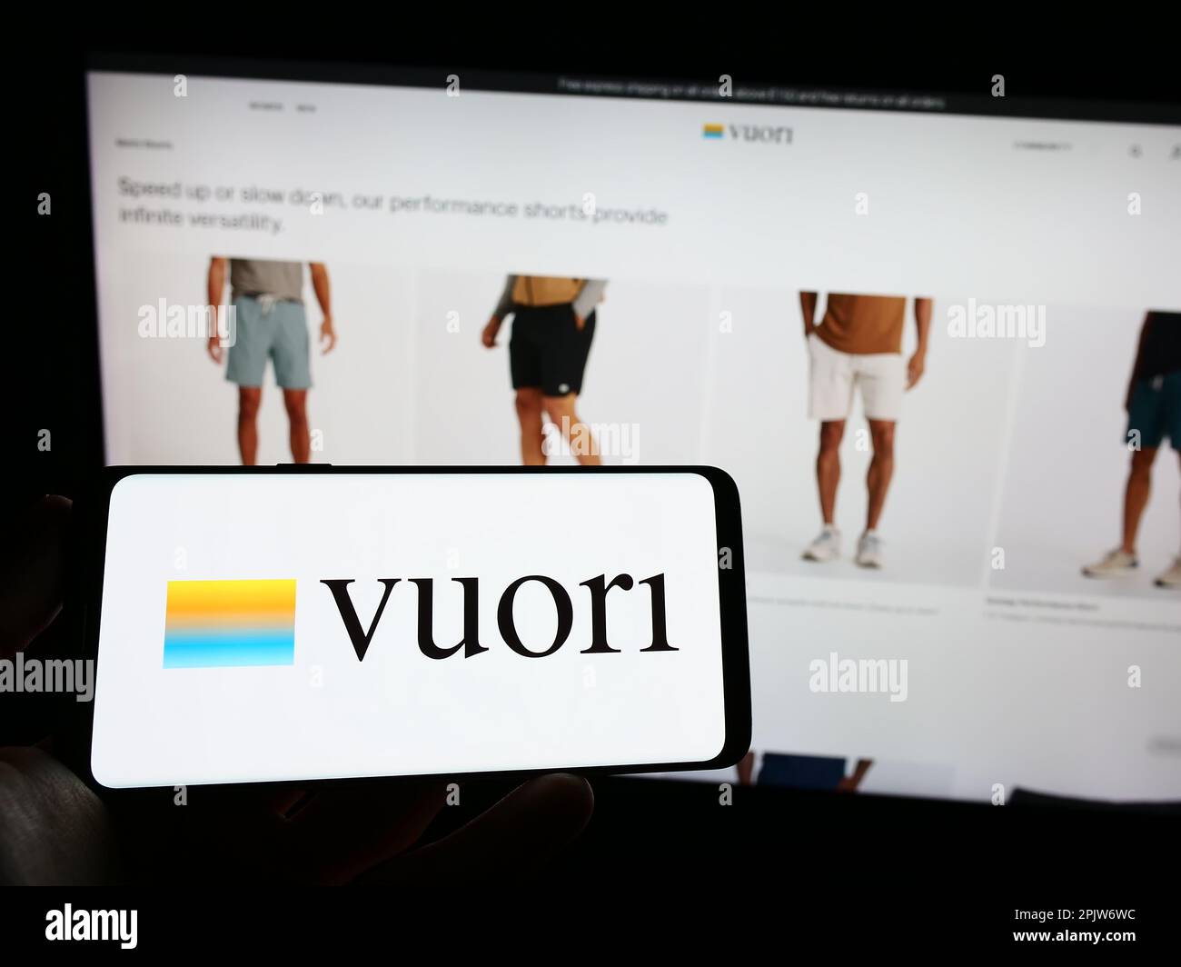 Person holding mobile phone with logo of American apparel e-commerce company Vuori Inc. on screen in front of web page. Focus on phone display. Stock Photo