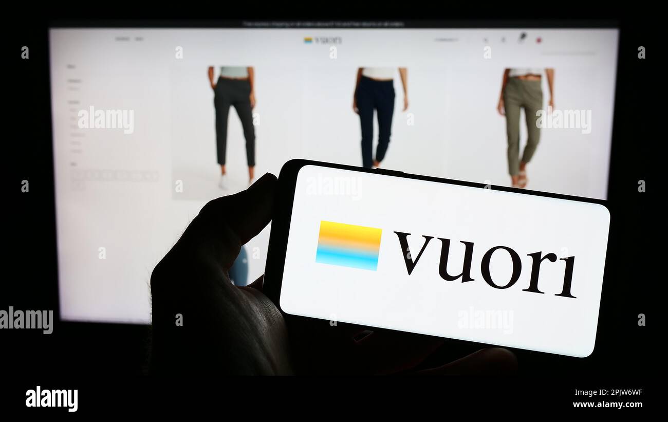 Person holding cellphone with logo of US apparel e-commerce company Vuori Inc. on screen in front of business webpage. Focus on phone display. Stock Photo