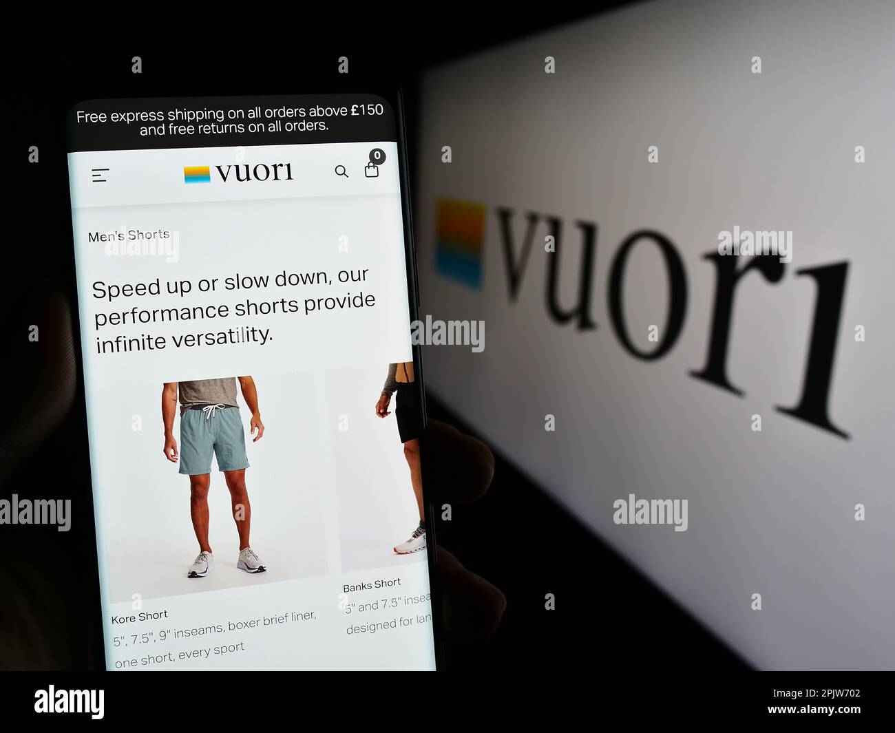 Person holding smartphone with web page of US apparel e-commerce company Vuori Inc. on screen in front of logo. Focus on center of phone display. Stock Photo