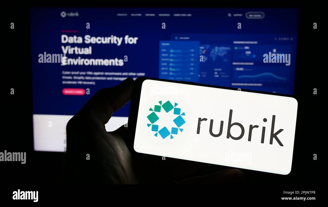Person holding cellphone with logo of US data security company Rubrik Inc. on screen in front of business webpage. Focus on phone display. Stock Photo