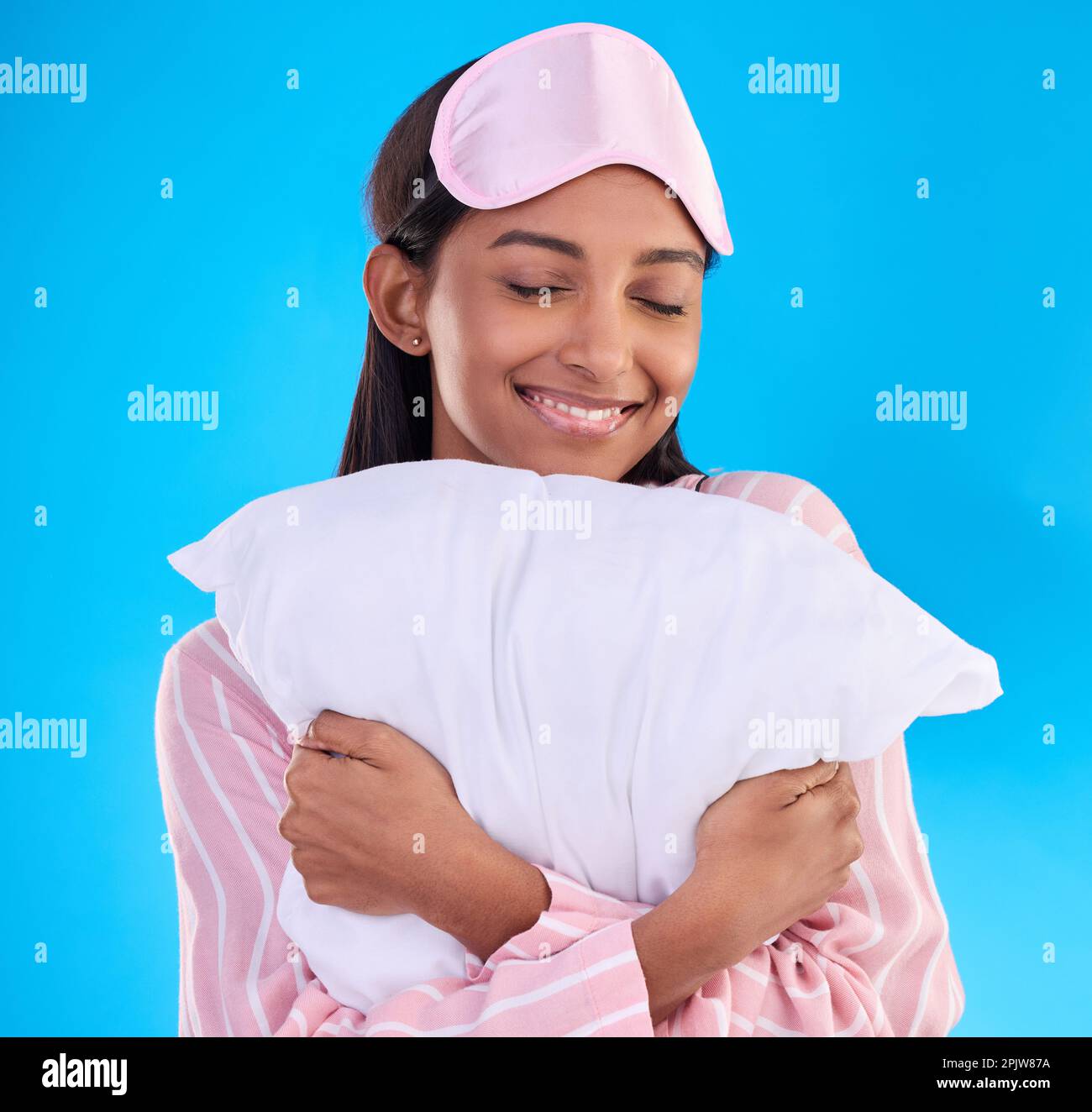 Bedtime, happy and a woman hugging a pillow isolated on a blue