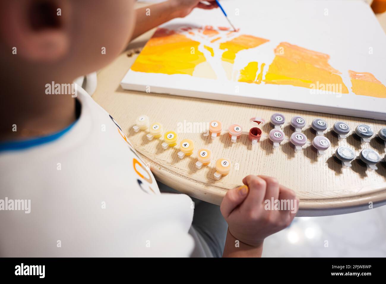 Painting on canvas by numbers. A child is holding a brush and