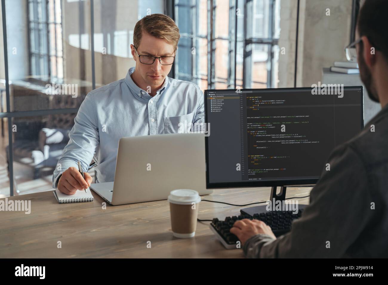 Two IT specialists co-working at office, working on new product, analyzing data, programming new software Stock Photo