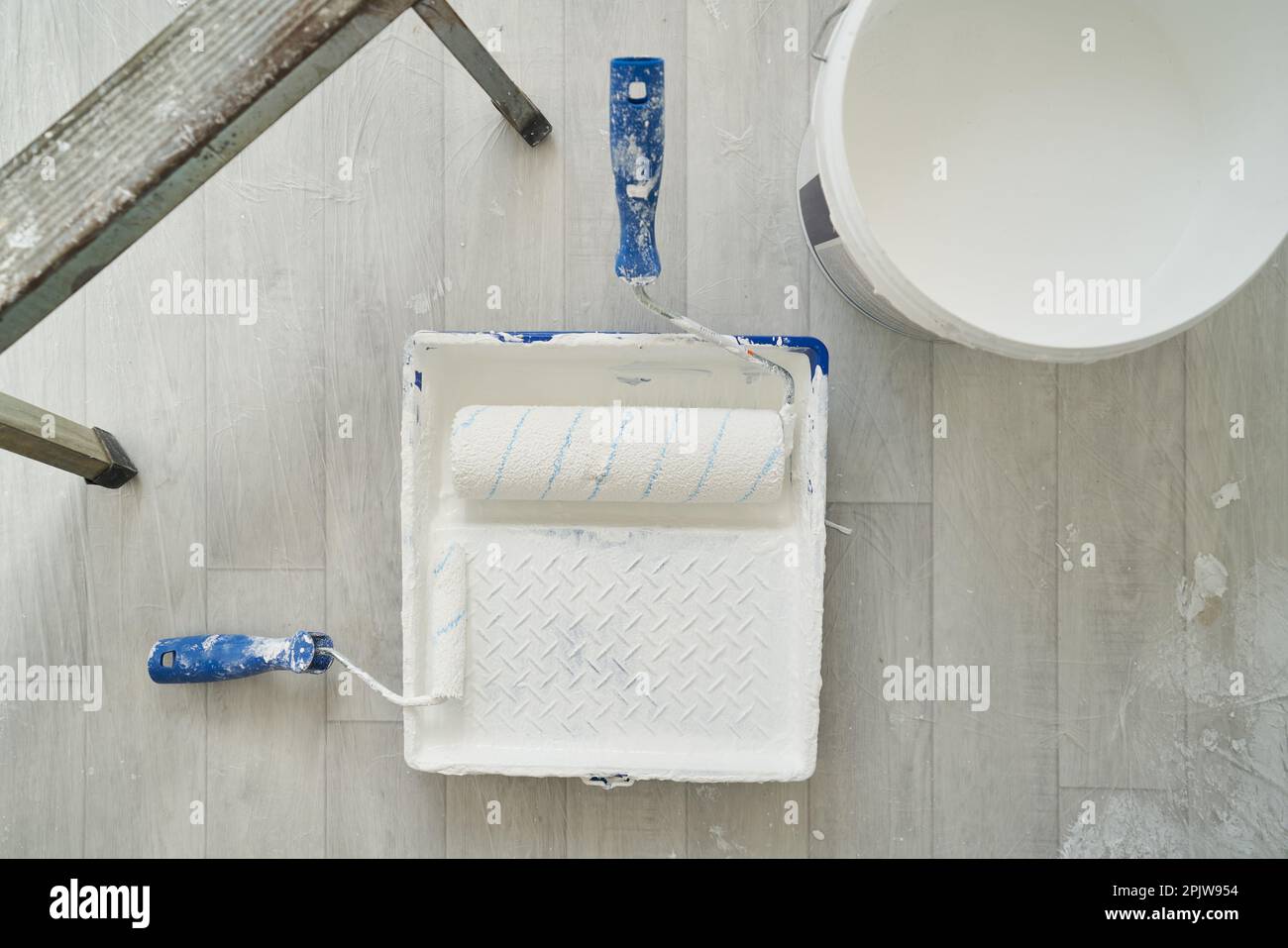 Paint tray with brush roller and bucket of paint and stairs. Concept of repair and finishing